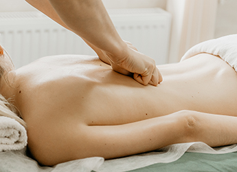 Masseur doing back massage to young woman.